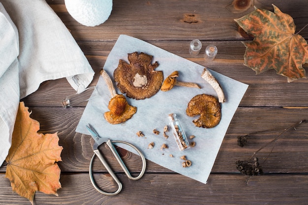 Gedroogde gehakte vliegenzwammen gestapeld in een kleine pot en droge champignons op perkament en schaar op een houten tafel. microdosering en alternatieve geneeskunde. bovenaanzicht