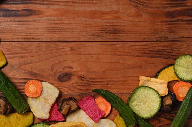 Gedroogde mix groenten chips met okra, wortelen, pompoen, rode biet en shiitake paddestoelen op houten achtergrond. Ruimte kopiëren.