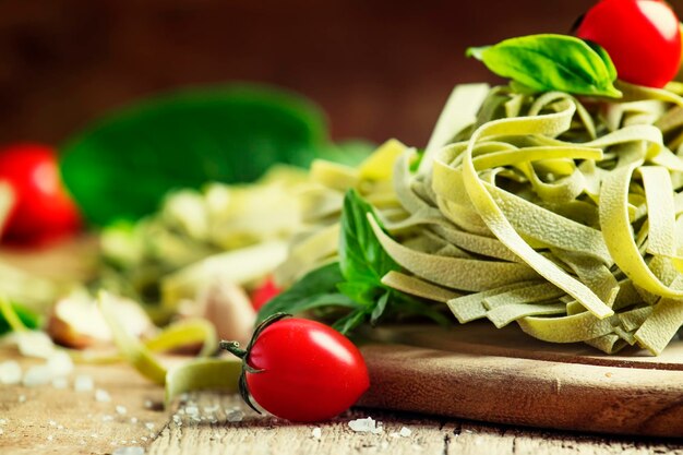 Gedroogde pasta met spinazie, tomaten, knoflook en basilicum, getinte afbeelding rustieke stijl vintage hout achtergrond selectieve aandacht