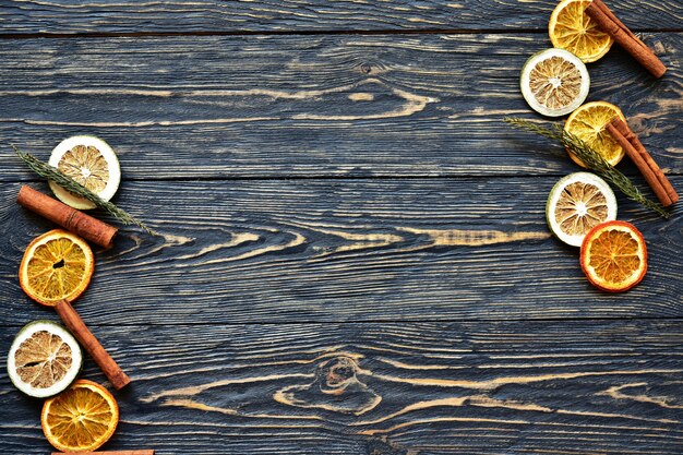 Gedroogde plakjes sinaasappel en limoen en kaneelstokjes op een donkere houten achtergrond. Natuurlijk licht. Bovenaanzicht.