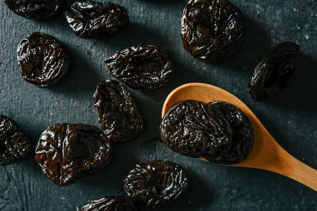 Gedroogde pruimen op een houten lepel en een donkere achtergrond Gezonde biologische snack rijk aan vezels en antioxidanten perfect voor de spijsvertering en natuurlijke zoetheid in het dieet