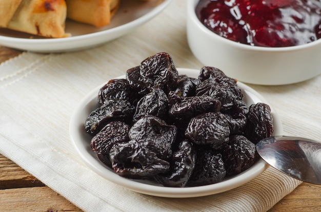 Gedroogde pruimen op kleine plaat met jam uit de pruimen op houten tafel