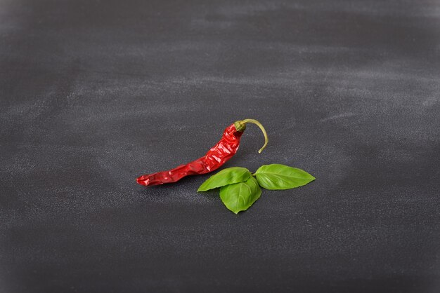 Gedroogde rode chili met basilicum blad op een donkere tafel.