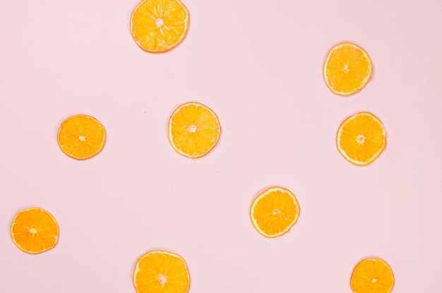 Gedroogde sinaasappelchips verspreid over roze achtergrond