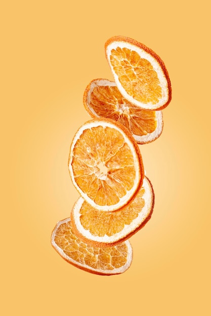 Gedroogde sinaasappels vliegen op een gele achtergrond