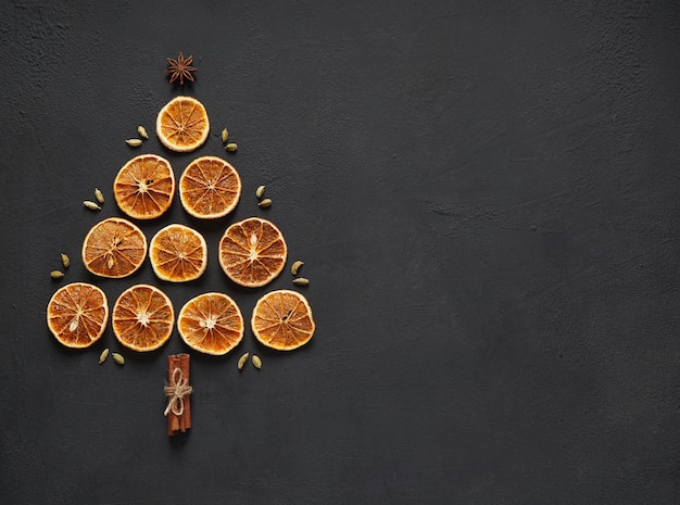 Gedroogde sinaasappelschijfjes lagen in de vorm van een kerstboom op een bord met kaneelstokjes, bovenaanzicht. kopieer ruimte