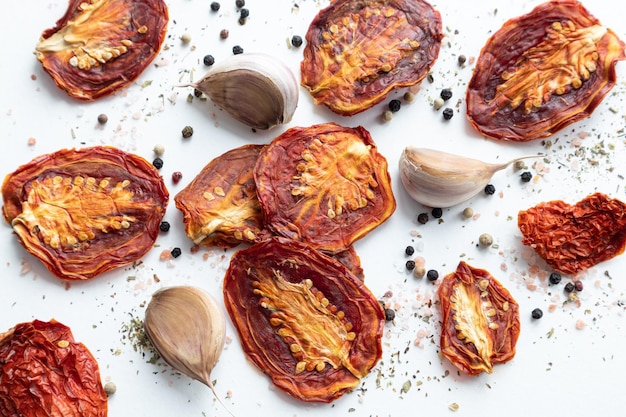 Gedroogde tomaten met zwarte peper en knoflook op een witte achtergrond