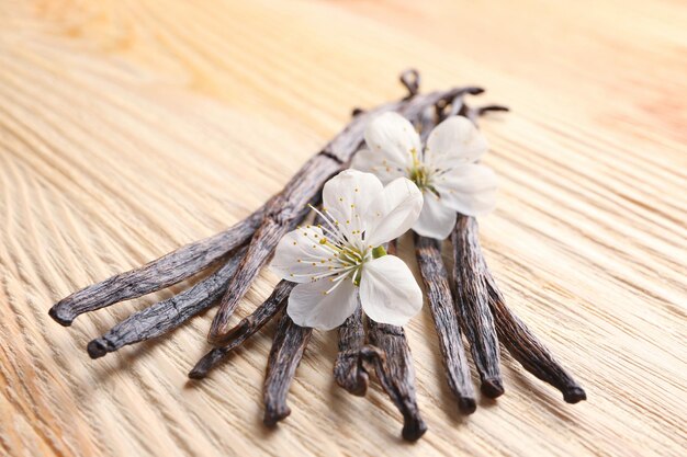 Gedroogde vanillestokjes en bloemen op houten close-up als achtergrond