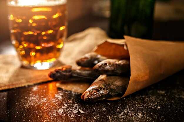 Gedroogde vis en vintage glas bier op een zwarte ondergrond