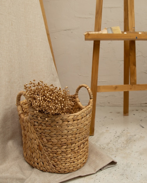 Foto gedroogde wilde bloemen in een rieten gevlochten mand in rustieke stijl op linnen en beton. het concept van natuurlijk decor in interieur