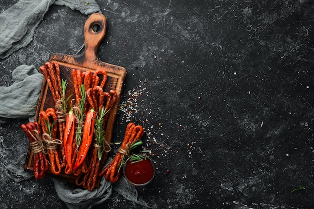 Gedroogde worstjes met chili peper op zwarte stenen achtergrond Chili pepers Kabanosy Bovenaanzicht Vrije ruimte voor uw tekst