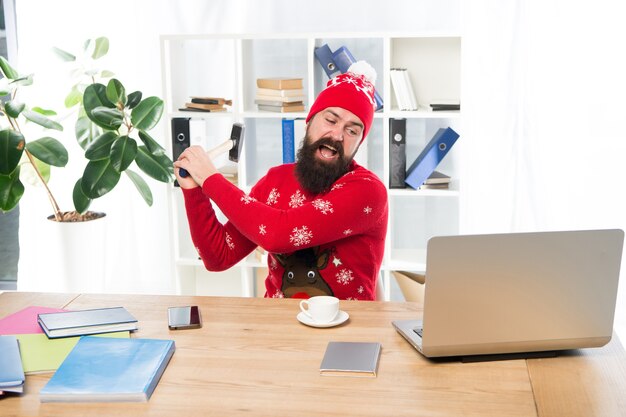 Gedwongen om op kerstavond te werken. Contractueel recht om niet te werken op eerste kerstdag. Gekke arbeider vernietigt laptop met hamer. Weiger te werken met Kerstmis. Werkgelegenheid rechten concept. Vrije dagen als betaald verlof.