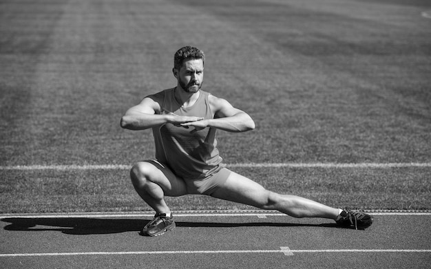 Geef nooit sportsucces op mannelijke atleet doe ochtendoefening warming-up training sportman flex spieren buiten gespierde man doe stretching man in yoga pose sport en gezonde levensstijl routine