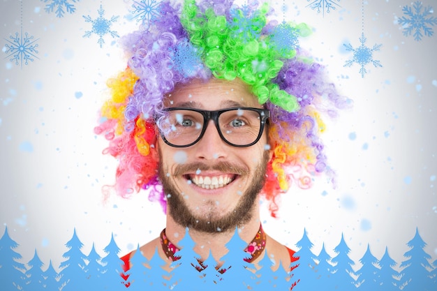 Geeky hipster in afro rainbow wig against snowflakes and fir trees in blue