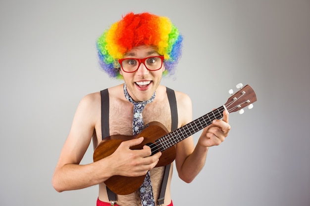 Geeky hipster in afro rainbow wig playing guitar