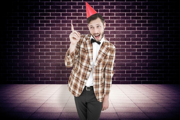 Geeky hipster in party hat  against purple vignette