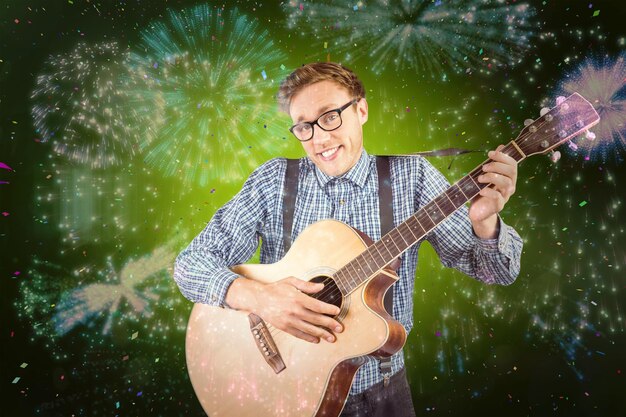 Geeky hipster playing the guitar against colourful fireworks exploding on black background