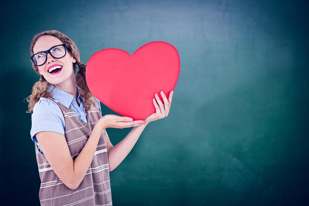 Geeky hipster vrouw met hartkaart tegen groen bord