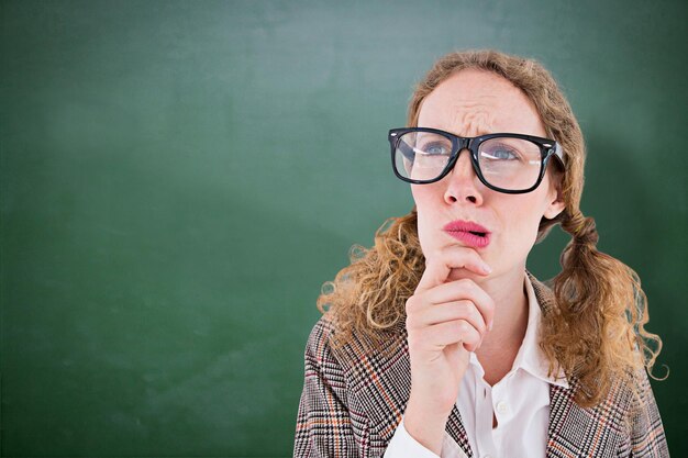 Photo geeky hipster woman thinking with hand on chin against green chalkboard