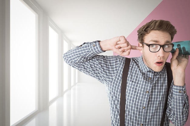 Geeky zakenman afluisteren met kop tegen moderne witte en roze kamer met raam