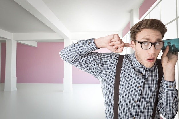 Foto geeky zakenman afluisteren met kop tegen moderne witte en roze kamer met raam