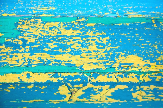 Geel-blauw-groen peeling verf textuur. Een houten oppervlak bedekt met verschillende lagen gebarsten verf