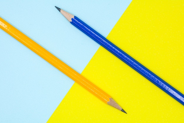 Geel en blauw potlood op een blauw en geel document - achtergrond