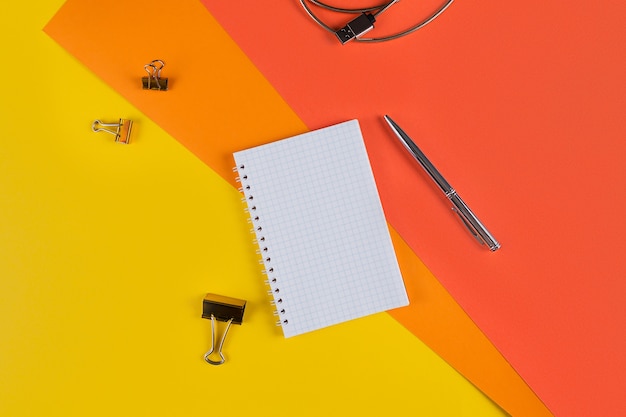 Geel en oranje bureau tafel met blanco notebook en andere kantoorbenodigdheden. Bovenaanzicht met kopie ruimte, plat leggen.