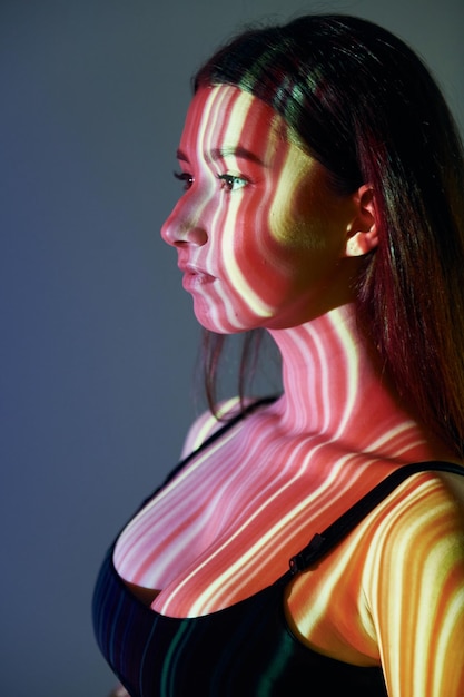 Geel en rood gekleurde lijnen Mooie jonge vrouw is in projector neonlichten in de studio