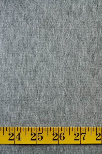 Geel meetlint ligt op een grijze gebreide stof