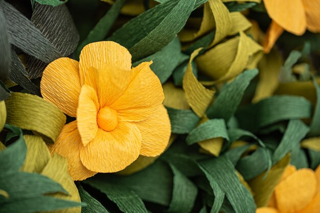 Geel papier bloemen onder groene bladeren