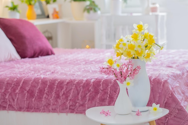 Geel-roze lentebloemen in vaas in moderne roze slaapkamer