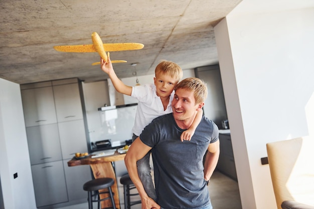 Geel speelgoedvliegtuig Vader en zoon zitten samen binnen thuis