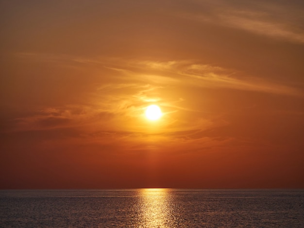 Geeloranje zonsondergang op zee of oceaan, strandkust