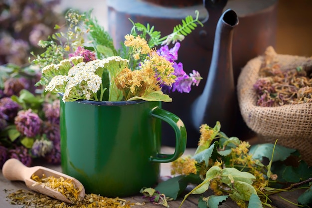 Geëmailleerde mok met zomergenezende kruiden oude theeketel en geneeskrachtige planten voor gezonde kruidenthee Kruidengeneeskunde