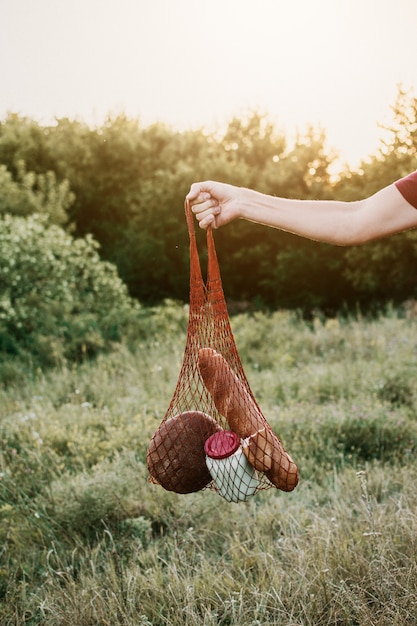 Geen afval, geen plastic, ecologische levensstijl. Mannenhand met rustieke herbruikbare katoenen nettas