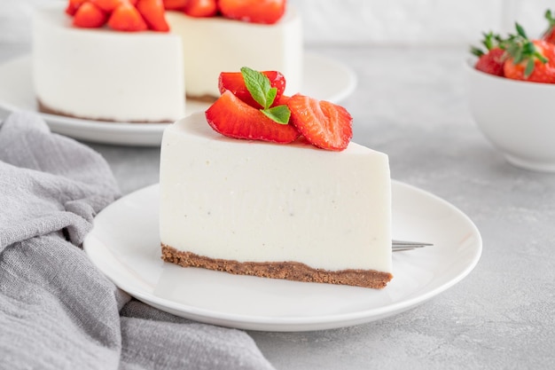 Geen gebakken cheesecake met verse aardbeien en munt erop op een wit bord