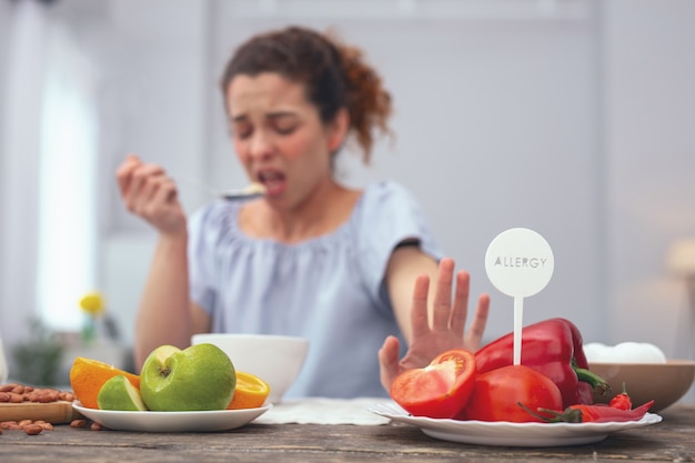 Geen groenten. Jonge vrouw kijkt ongelukkig terwijl ze bewust handelt terwijl ze weigert groenten te consumeren die haar allergische reactie uitlokken