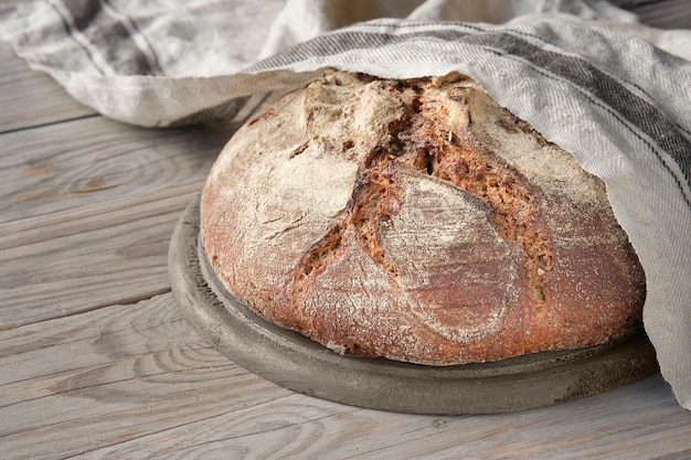 Geen kneed handgemaakt brood op snijplank op hout met linnen handdoek speltoren Duits Bauernbrot betekent Boerenbrood in het Engels Volkoren roggebrood thuis gebakken in keramische pan