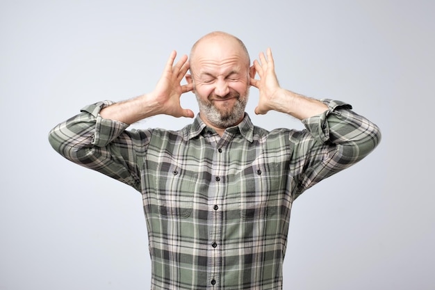Foto geërgerde volwassen man die oren stopt met vingers