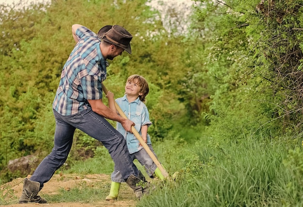 Geest van avonturen Avontuurlijke jacht op schatten Kleine helper in de tuin Schattig kind in de natuur plezier cowboy vader Vind schatten Kleine jongen en vader met schop op zoek naar schatten