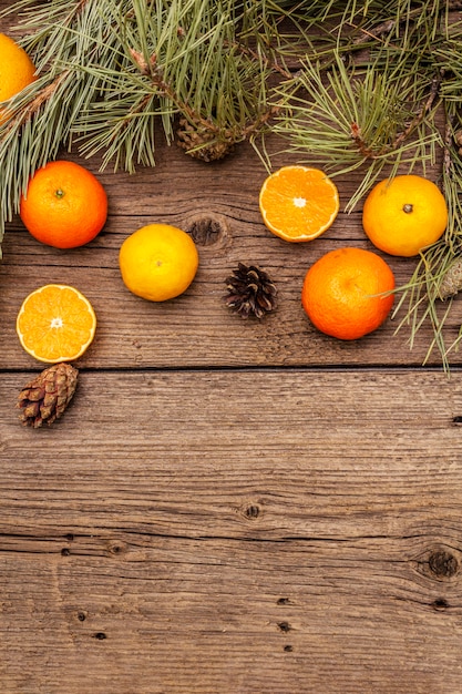 Geestkerstmis op houten tafel. verse sinaasappels, mandarijnen, pijnboomtakken en kegels. natuurdecoraties, vintage houten planken