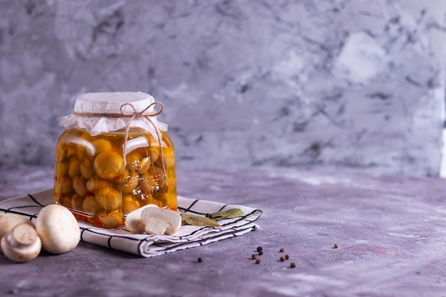 Gefermenteerde champignon champignons in blik in een glazen pot met knoflook, laurierblad en een wit servet