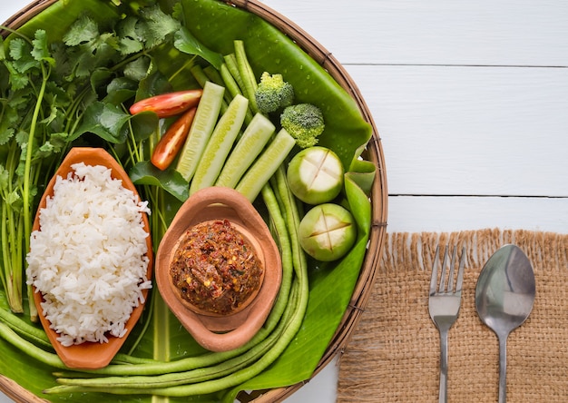 Gefermenteerde vis pittige dip met verse groenten, komkommer, kousenband, broccoli, koriander, tomaat, aubergine op houten bord