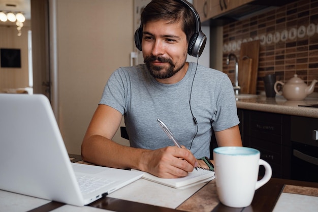 Gefocuste jonge man draagt een koptelefoon om online te studeren