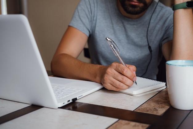Gefocuste jonge man draagt een koptelefoon om online te studeren