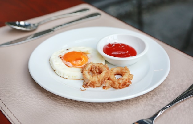 gefrituurde calamariringen en gebakken ei met tomatensaus op plaat