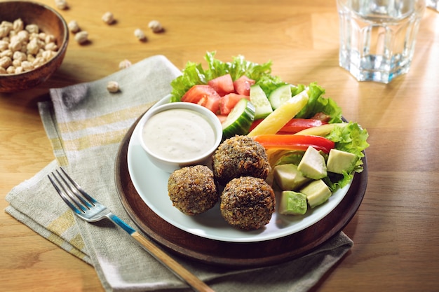 Gefrituurde falafelballetjes geserveerd met verse groenten en saus