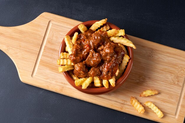 Gefrituurde friet met goulash in een rood bord