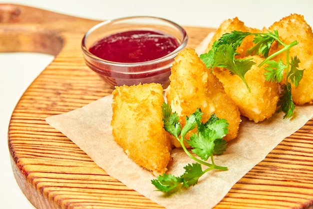 Gefrituurde kaasnuggets met bessensaus op een houten bord